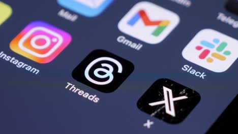 Smartphone-screen-with-app-icons,-user-swiping-to-Threads-app,-blurred-background