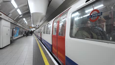 Bakerloo-Line-Train-Departing-At-Oxford-Street-Station-Platform-With-Commuters-Walking-Behind-Yellow-Line