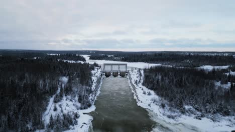 Langer-Clip,-Landschaftsaufnahme-Aus-Der-Luft-Mit-Einer-Drohne,-Rauschendes-Wasser,-Riesiger-Staudamm-Des-Notigi-Wasserkraftwerks-Im-Verschneiten-Winter-Im-Norden-Manitoba,-Kanada