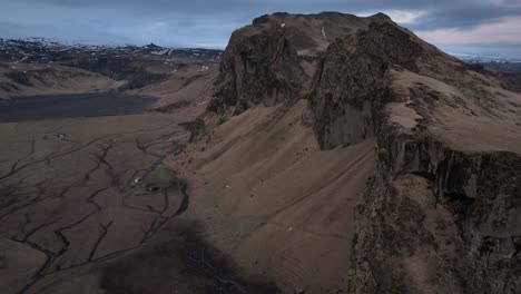 Aerial-view-of-a-scenic-cliff-on-a-mountain-in-Iceland,-with-a-dramatic-evening-cloudscape