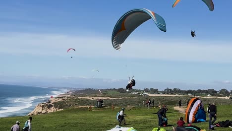 Tandem-Para-gliders-come-in-for-a-smooth-landing-and-sit-down-on-the-grass-at-Torrey-Pines-Gliderport-in-La-Jolla,-California
