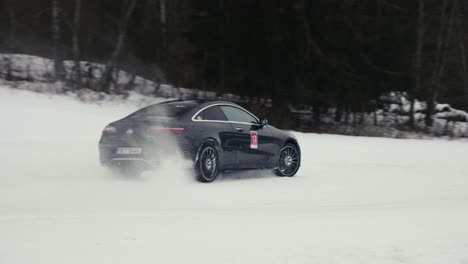 Driver-in-black-car-drive-aggressively-on-snowy-race-track-during-drift-event