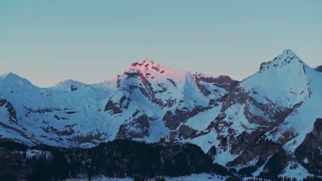 Witness-the-ethereal-charm-of-sunrise-over-a-snow-capped-mountain-range-silhouette-through-this-mesmerizing-drone-footage