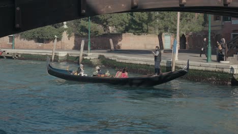 Gondola-cruise-under-a-bridge-in-Venice,-Italy