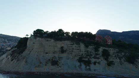 Häuser-An-Einer-Klippe-Mit-Blick-Auf-Das-Meer-Bei-Sonnenuntergang-In-Alicante,-Spanien,-Mit-Ruhigem-Wasser