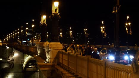 Budapest-city-center-view-with-Margit-Bridge-and-Danube-river-at-night,-light-reflections,-traffic-and-people-moving,-medium-shot