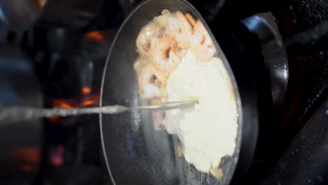 Adding-sour-cream-to-cooking-shrimp-in-a-cooking-pan