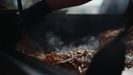 Stirring-steaming-fried-noodles-with-metal-spatulas-on-festival-grill