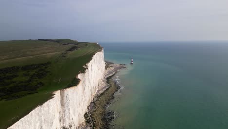 Aerial-shot-of-the-shore,-flying-along-the-cliff-towards-beachy-head-light-house-on-a-sunny-day