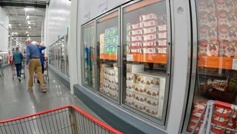 POV---Slowly-pushing-the-grocery-cart-past-freezer-cases-that-contain-ice-cream-and-then-to-frozen-vegetables-and-fruit-at-local-Costco