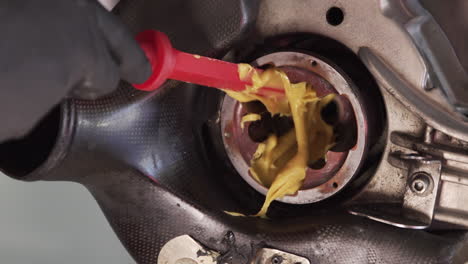 Grease-being-added-to-the-"Outer-CV-Joint"-on-car-using-a-red-plastic-rod-to-spread-it-around