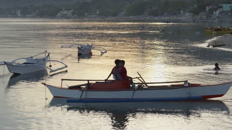 Junge-Philippinische-Kinder-Sitzen-Bei-Sonnenuntergang-Im-Meer-Auf-Einem-Traditionellen-Bankga-Fischerboot