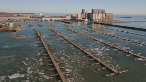 Port-colborne's-industrial-docks-and-ice-covered-water-in-clear-weather,-static-shot,-aerial-view