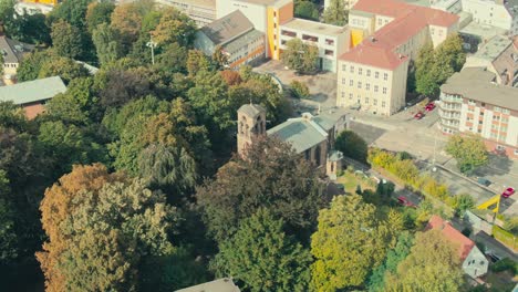 A-church-surrounded-by-trees-in-an-urban-area,-daylight,-aerial-view