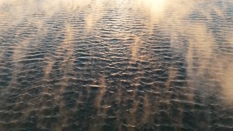 Aerial-Low-Flying-Over-Waves-With-Floating-Mist,-Tilt-Up-To-Reveal-Golden-Hour-Sunset-Near-Bjorvika,-Rising-Shot