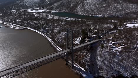 Eine-Luftaufnahme-Der-Bear-Mountain-Bridge-An-Einem-Sonnigen-Tag-Mit-Einem-See-Im-Hintergrund