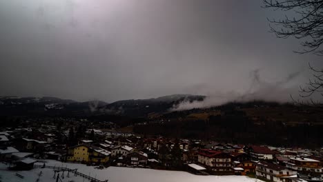 Fog-flowing-above-Kirchberg-township-in-Alps-in-winter-season,-time-lapse-view