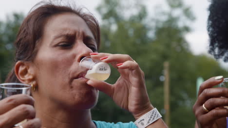 Woman-tasting-a-sample-of-beer-outside-with-friends