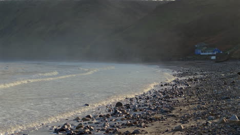 Niedriger-Drohnenschuss-über-Dem-Strand-Von-Runswick-Bay-Bei-Flut-Mit-Klippen-Dahinter