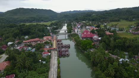 Aerial-Drone-Fly-Above-loboc-river-Philippines-Wet-River-Green-HIlls-Landscape-with-Small-Village-and-Red-Tile-Houses