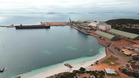aerial-view-over-Esperance-industrial-harbour-with-a-cargo-ship-beeing-loaded,-western-australia