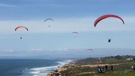 Lots-of-para-gliders-flying-when-one-tandem-para-glider-flying-close-up-comes-in-for-a-smooth-landing-at-Torrey-Pines-Gliderport-in-La-Jolla,-California