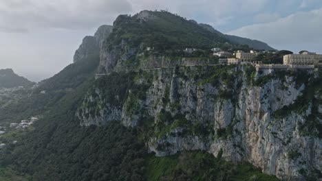 Cliffside-view-of-Capri-with-lush-greenery-and-historic-architecture,-under-a-clear-sky