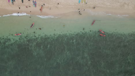 Sadranan-beach-in-indonesia-with-people-and-kayaks-on-clear-waters,-aerial-view
