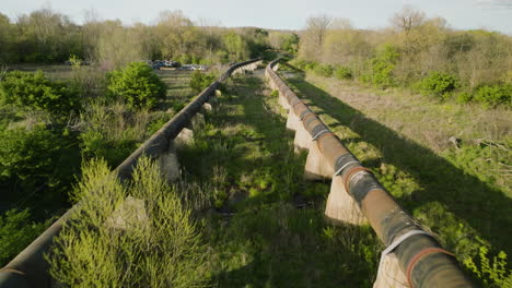 Elevated-view-of-rusted-pipelines-at-a-junkyard-in-Fayetteville,-AR,-lush-greenery