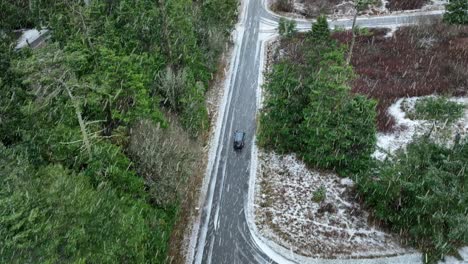 Overhead-view-of-car-driving-on-rural-road-during-snow-storm