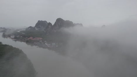 Aerial-Shot-Through-Foggy-Clouds-Over-Ao-Phang-Na-National-Park-HQ-with-Views-of-Mangroves-and-Limestone-Cliffs