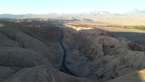 Drone-hovers-over-Atacama,-Volcan-Licancabur,-displaying-the-highway-with-some-traffic