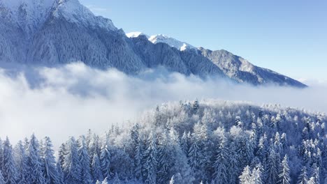 Verschneiter-Wald-Mit-Berggipfeln-Und-Wolken-Im-Bucegi-Gebirge,-Luftaufnahme