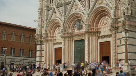 Timelapse-and-tilt-of-of-the-15th-century-built-Siena-Cathedral-in-Tuscany,-Italy-with-tourists-gathered-on-the-steps-beneath