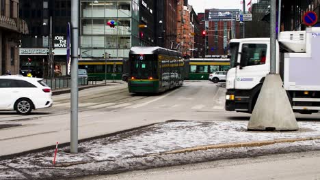 Belebte-Helsinki-Kreuzung-Mit-Fahrzeugen-Und-Straßenbahn,-Verschneiter-Tag,-Städtische-Szene,-Bedeckter-Himmel