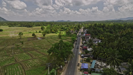 Ibbagamuwa-Sri-Lanka-Aerial-v4-low-flyover-small-rural-village-town-along-Dambulla-road-capturing-farming-fields,-jungle-landscape-and-hillside-views---Shot-with-Mavic-3-Cine---April-2023