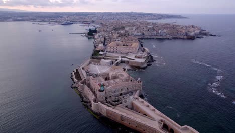 Aerial-toward-Island-of-Ortigia-historical-town-at-dusk,-Sicily-Italy