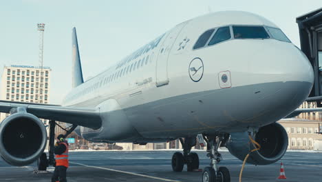 Lufthansa-Airbus-A320-Estacionado-En-La-Puerta-Del-Aeropuerto-De-Tallin-Y-Technopolis-Ülemiste-Visible-Al-Fondo