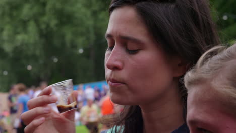 Nahaufnahme-Einer-Erwachsenen-Frau,-Die-Auf-Einem-Bierfest-Dunkles-Bier-In-Einem-Kleinen-Plastikbecher-Probiert