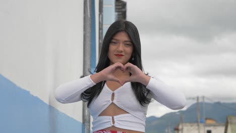 Ein-Wunderschönes-Latina-Mädchen-Faltet-Ihre-Hände-Zu-Einem-Symbol-Der-Liebe-Auf-Einer-Landstraße-In-Der-Stadt-Machachi,-Ecuador