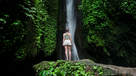 Slomo-shot-from-rear-of-female-caucasian-traveler-looking-up-at-Leke-Leke-falls