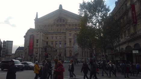 Slomo-shot-of-people-walking-across-street-in-front-of-Palais-Garnier-in-Paris