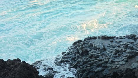 Splashing-water-hitting-the-rocks-on-the-seaside,-static-closeup-slow-motion
