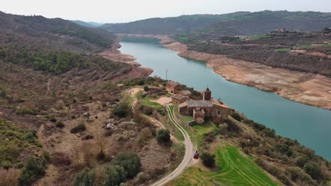 Aerial-flyback-of-Rialb-tower-complex-with-river-and-surrounding-landscape,-Lleida-in-Spain