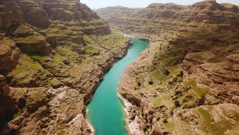 Mountain-in-background-in-hazy-day-in-nature-the-green-fresh-vivid-color-of-river-in-the-adventure-canyon-dezful-mud-rock-clay-cliff-in-outdoor-hiking-travel-natural-view-of-wild-country-in-Iran