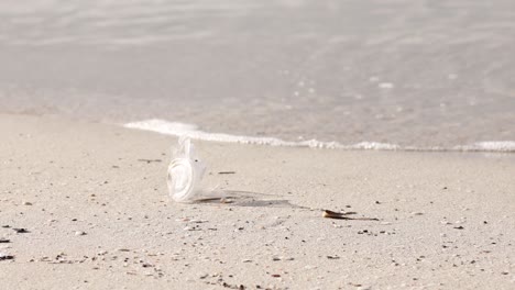 Weggeworfener-Plastikbecher-Liegt-An-Einem-Sandstrand,-Wellen-Im-Hintergrund,-Umweltproblem