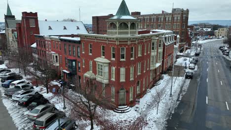 Vista-De-Esquina-De-Un-Edificio-De-Ladrillo-Rojo-Con-Una-Torre,-Calles-Cubiertas-De-Nieve-Y-Autos-Estacionados-En-Un-Día-Nublado