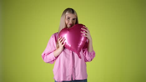 Una-Joven-Rubia-Caucásica-Juega-Con-Un-Globo-En-Forma-De-Hogar-Sonriendo,-Estudio