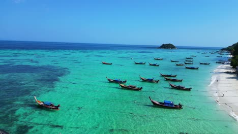 longtail-boats-beach-rocky-cliff-island-turquoise-blue-sea