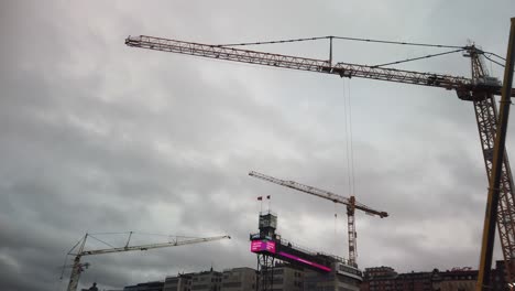Large-construction-crane-turns-with-cloudy-sky-and-more-cranes-in-background